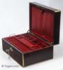 JB446: Figured rosewood and brass surround box circa 1830. A box veneered in figured rosewood box strengthened and accented with brass. The top central plaque bears initials in a stylized Gothic  script and a coronet,  probably of French nobility. There is also a brass inset of a lift-up aid on the front part of the lid. The box has extra support hinges on the sides which enable it to stay open at the same angle. The interior tray is original as is the silk faced envelope. Additional velvet covers protect and render the interior more useable. Working key.  