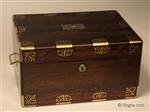 JB634: Figured rosewood box with rounded edges in alternating brass and rosewood having fine inlaid brass accents depicting stylized neo-classical motifs . The box is of high quality, which continues into the compartmentalized interior. There is a lockable side drawer of dovetail construction fitted for jewelry. It is lined in velvet and embossed leather. The box has its original leather covered lift-out tray. There is a document wallet in the lid with a mirror behind. Both the main lock and the drawer lock are working and have the same key. Circa 1825.
 