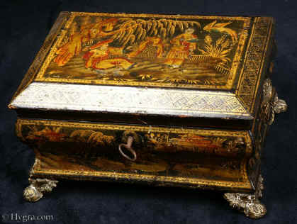 SB425:  Sewing box with  Japanned, raised and polychromed decoration on this sewing box depicting  a truly golden vision of Cathay. Figures relax in a garden with a distant rock in the background and the ho-ho bird above. This is a relatively late example of such work and it does not have an overall varnish. Note how the gold and the colors have remained brighter than in earlier examples. Circa 1820. 