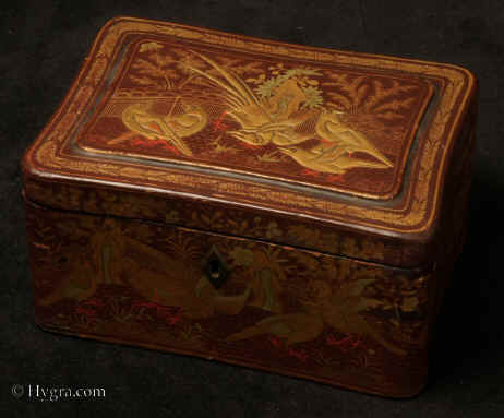 TC130:A Chinese export lacquer tea caddy in reddish earth colored lacquer having rounded corners decorated with two colors of gold depicting groups of birds highlighted in red lacquer. Circa 1840.Enlarge Picture